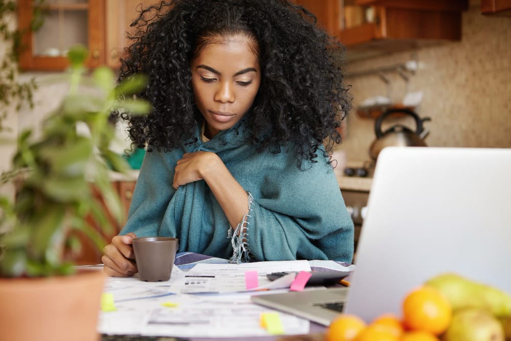 A woman working on her passive income on her kitchen table with a laptop