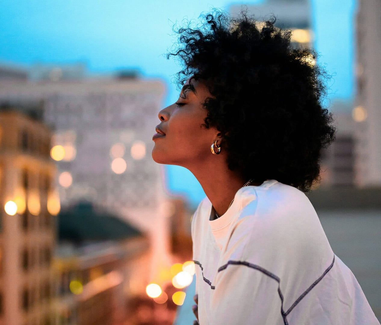 A woman gazing out over a city at sunset, reflecting on her life and finding hope in The Beauty of a Story Redeemed by Grace.