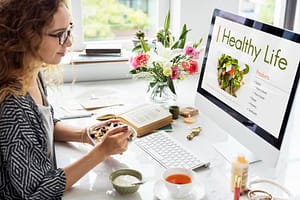 a woman sitting at a desk eating a bowl of cereal