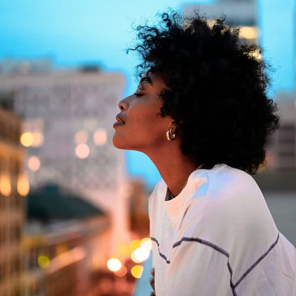 A woman gazing out over a city at sunset, reflecting on her life and finding hope in The Beauty of a Story Redeemed by Grace.