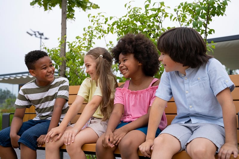 a group of children sitting on a bench- how to help your kids make friends