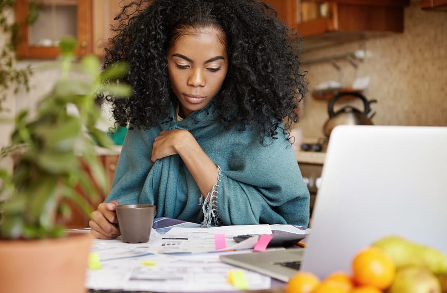 A woman working on her passive income on her kitchen table with a laptop