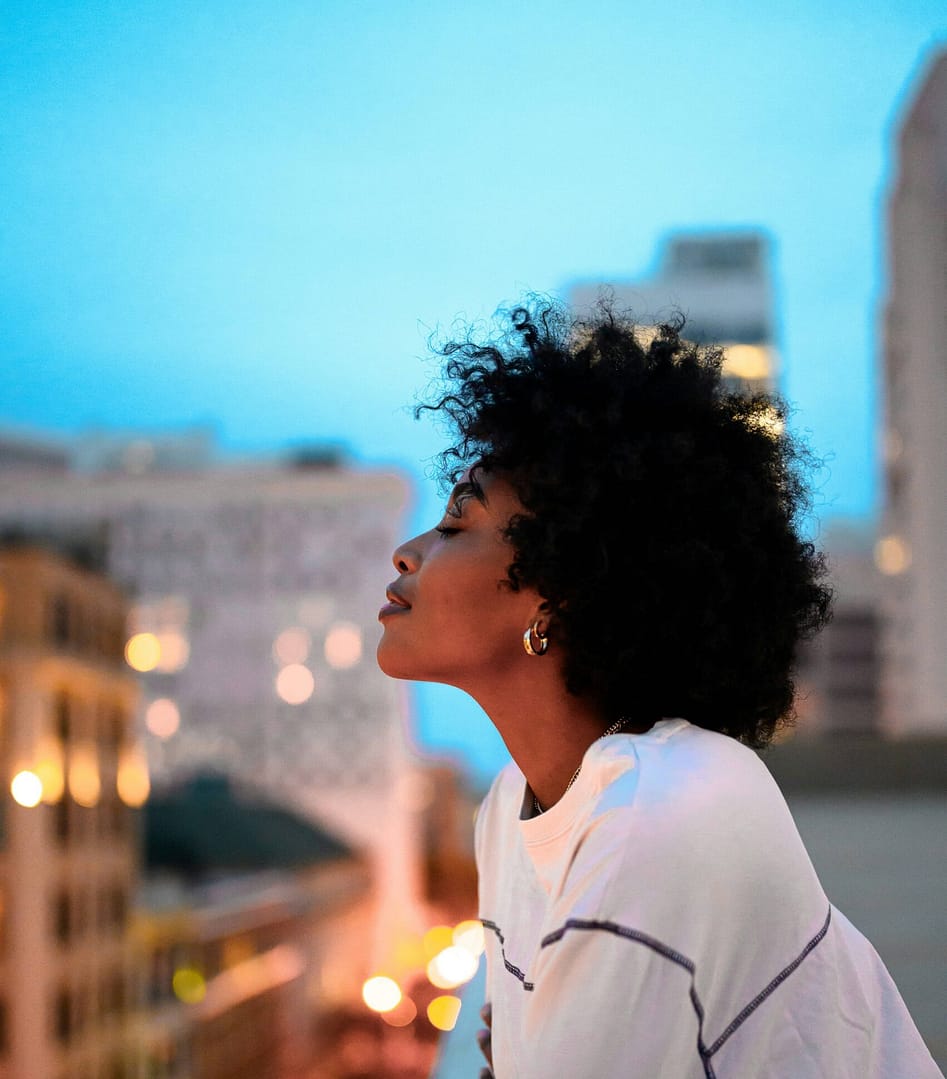 A woman gazing out over a city at sunset, reflecting on her life and finding hope in The Beauty of a Story Redeemed by Grace.